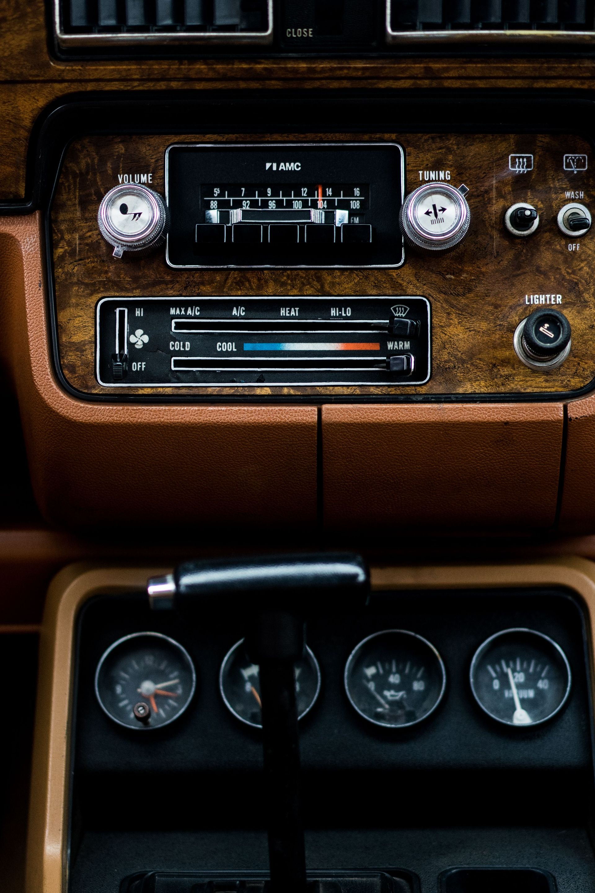 Close-up of a vintage car dashboard with radio and gauges, showcasing retro design.